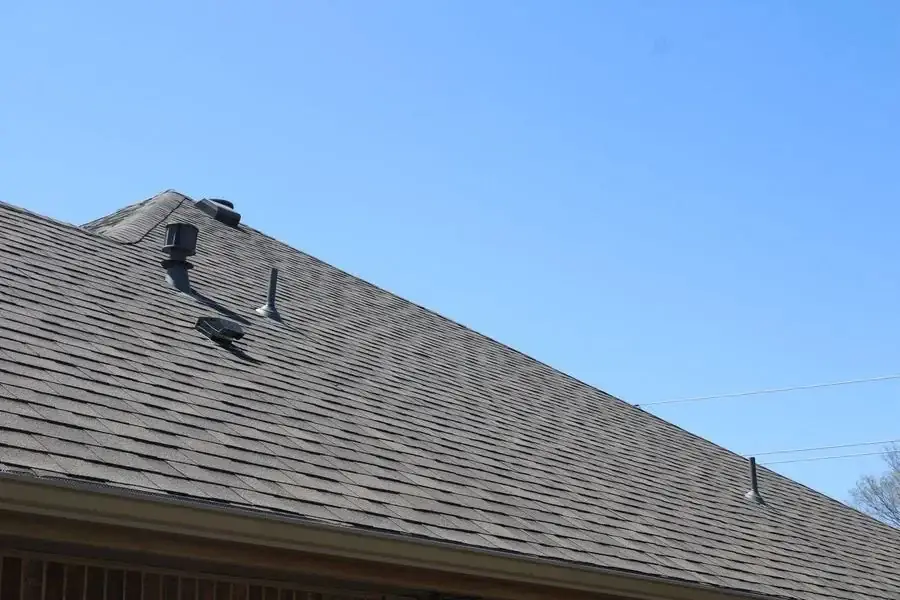 Close view of a dark gray architectural shingle field with roof vents and pipe boots