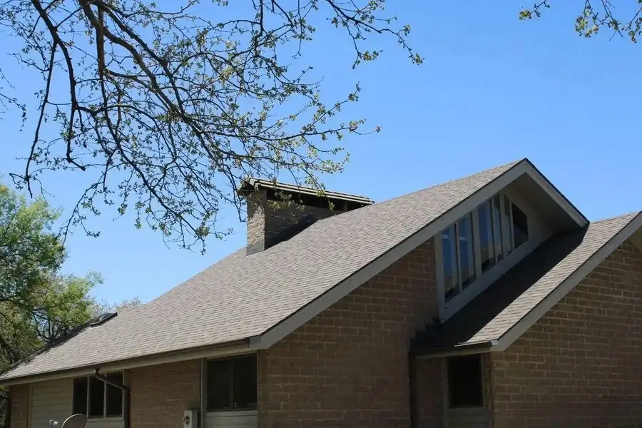 Brick home with a glass-filled front gable under a new gray shingle roof